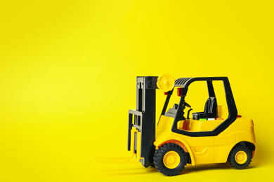 Toy forklift on yellow background, space for text. Logistics and wholesale concept