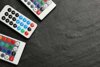 Remote controls on black table, flat lay. Space for text