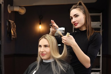Professional hairdresser cutting woman's hair in salon