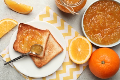 Delicious orange marmalade and toasts on light table, flat lay