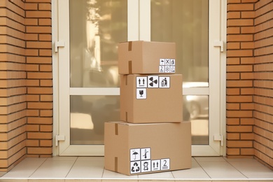 Cardboard boxes with different packaging symbols on floor near entrance. Parcel delivery