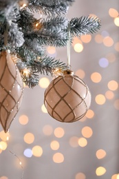 Christmas tree decorated with holiday baubles against blurred lights, closeup
