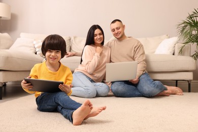 Happy family with gadgets on floor at home