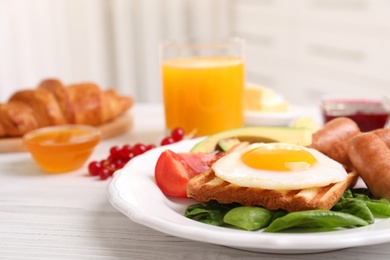Delicious breakfast with fried egg on white wooden table, closeup
