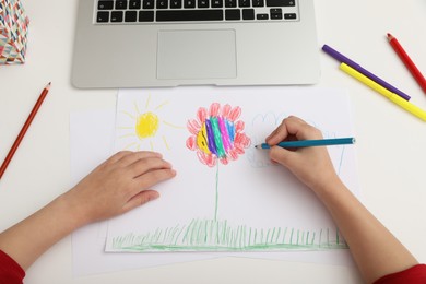 Little girl drawing on paper with pencil at online lesson indoors, above view. Distance learning