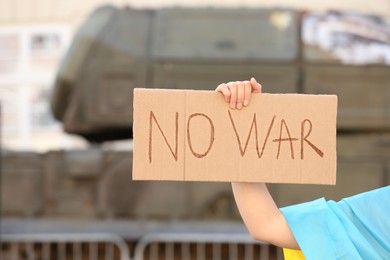 Woman holding poster with words No War outdoors, closeup