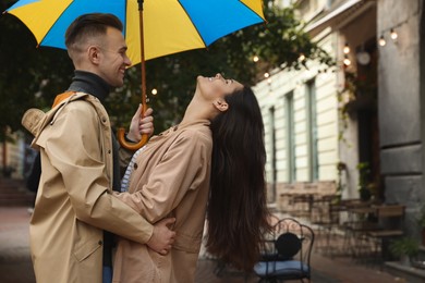 Photo of Lovely young couple with umbrella together under rain on city street