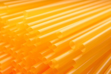 Heap of yellow plastic straws for drinks as background, closeup