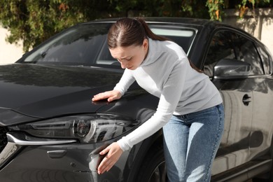 Photo of Stressed woman near car with scratch outdoors