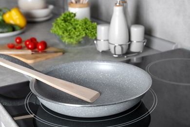 Frying pan with spatula on cooktop in kitchen. Cooking utensils