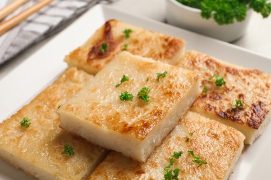 Delicious turnip cake with parsley on light table, closeup