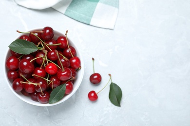 Sweet juicy cherries with leaves on grey marble table, flat lay. Space for text