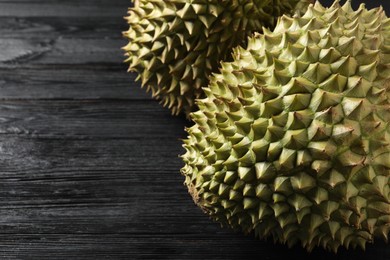 Ripe durians on black wooden table, closeup. Space for text