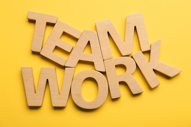 Photo of Job concept. Words Team Work made of wooden letters on yellow background, flat lay