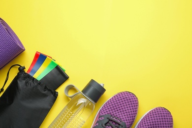 Photo of Flat lay composition with fitness elastic bands on yellow background Space for text