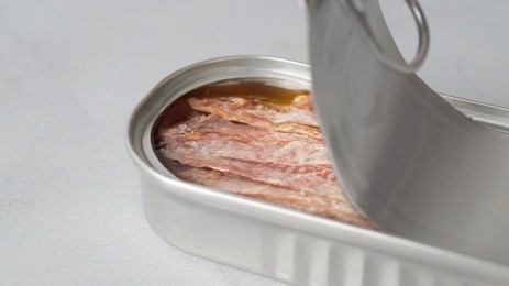 Photo of Anchovy fillets in open tin can on table, closeup