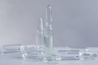 Pharmaceutical ampoules with medication on white table against light background