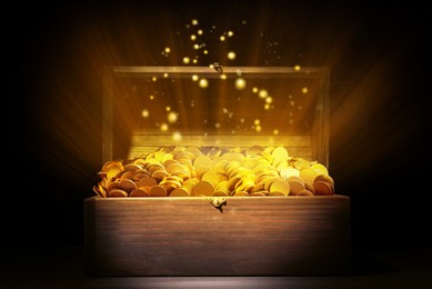 Image of Open treasure chest with gold coins on table against black background