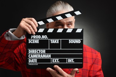 Photo of Senior actor with clapperboard on black background. Film industry