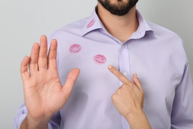 Woman pointing at lipstick kiss mark on her husband's shirt, closeup