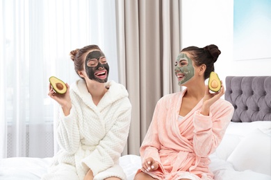 Young friends with facial masks having fun in bedroom at pamper party