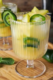 Photo of Spicy cocktail with jalapeno and carambola on wooden table, closeup