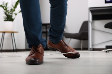 Photo of Man tripping over cord in office, closeup