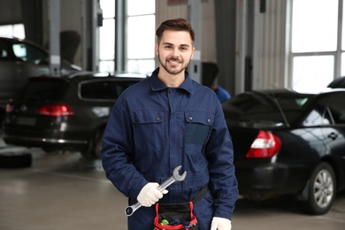 Portrait of technician with wrench at automobile repair shop