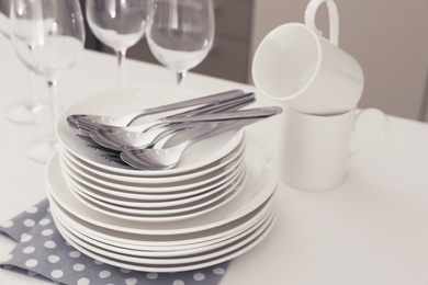 Clean dishes, glasses, cups and cutlery on table in kitchen