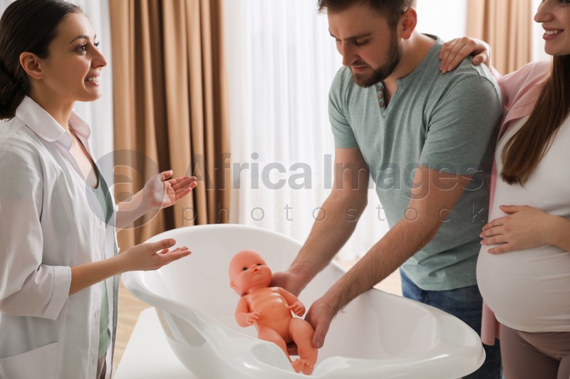 Man with pregnant wife learning how to bathe baby at courses for expectant parents indoors