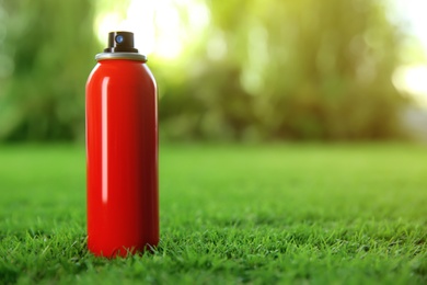 Bottle of insect repellent spray on green grass. Space for text