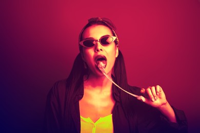 Image of Fashionable young woman with chewing bubblegum in neon lights