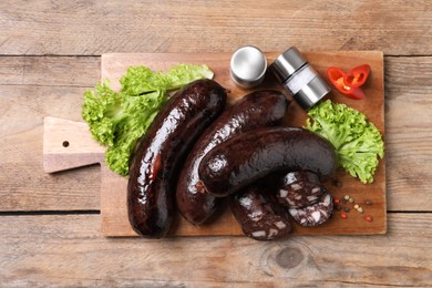 Tasty blood sausages served on wooden table, top view