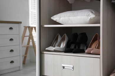 Wardrobe closet with different stylish shoes and home stuff in room