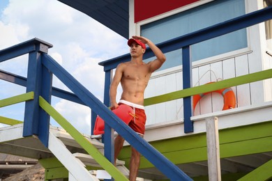 Handsome lifeguard with life buoy on watch tower