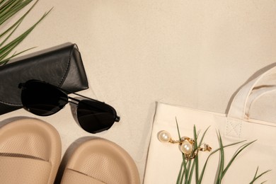 Flat lay composition with stylish sunglasses and black leather case on sand. Space for text