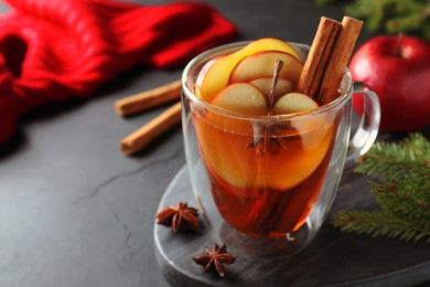 Aromatic hot mulled cider on black table. Space for text