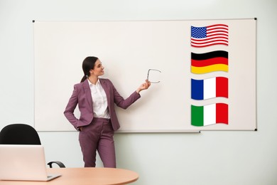 Foreign languages teacher near whiteboard with different flags in modern classroom