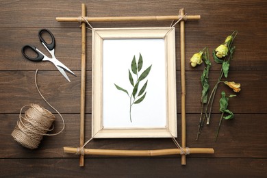 Photo of Flat lay composition with bamboo frame and dried plants on wooden table