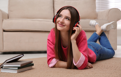 Woman listening to audiobook lying on floor at home

