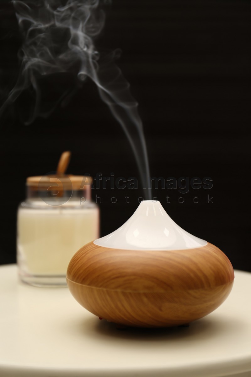 Aroma oil diffuser on table near black wall