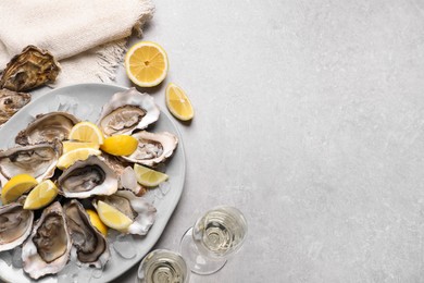 Fresh oysters with lemon and glasses of champagne on grey table, flat lay. Space for text