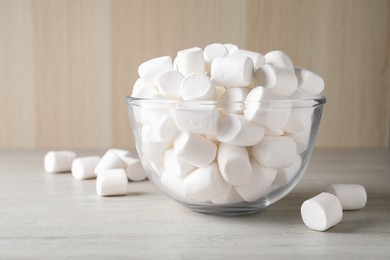 Delicious puffy marshmallows in bowl on wooden table