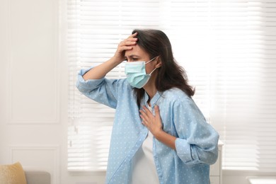 Mature woman with protective mask suffering from breathing problem at home