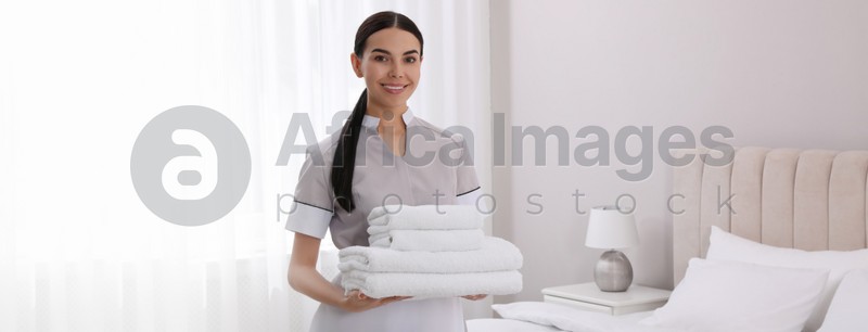 Chambermaid with stack of fresh towels in hotel room. Banner design