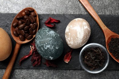 Photo of Naturally painted Easter eggs on grey table, top view. Hibiscus, tea and coffee beans used for coloring
