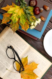 Maple leaves, book and glasses on wooden table, flat lay. Autumn atmosphere