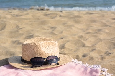 Photo of Hat with beautiful sunglasses on blanket near sea, space for text
