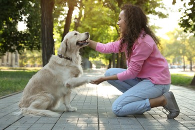 Young African-American woman and her Golden Retriever dog in park