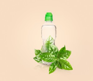 Bottle made of biodegradable plastic and green leaves on beige background